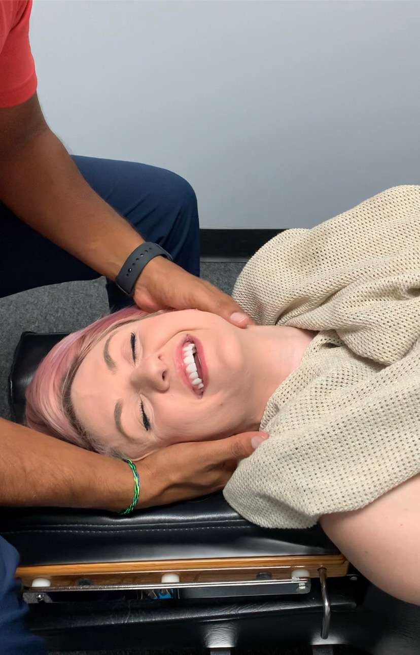 Smiling patient receiving a gentle neck adjustment at Breakaway Chiropractic in Frisco, TX