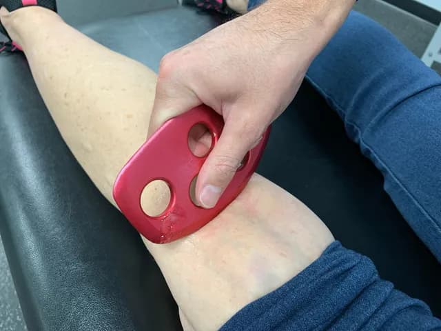 Instrument-assisted soft tissue work on a patient's leg at Breakaway Chiropractic in Frisco, TX